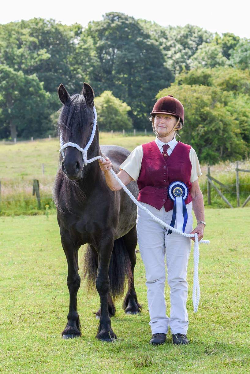black fell mare with her owner and rosette